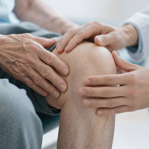 older man holding his knee with his doctor